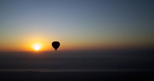 A hot air balloon with the rising sun at dawn over the Nile River