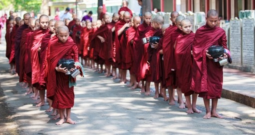 Young Buddhist monks walk to collect alms and offerings in the Monastery