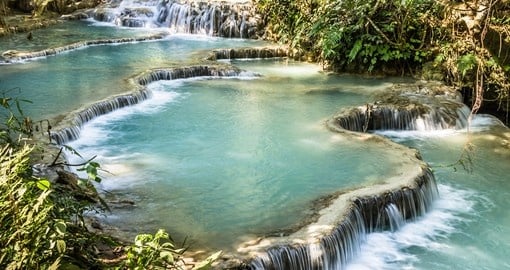Soak in the crystal clear pools underneath the Kuang Si Falls on your Laos Vacation