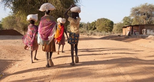 African girls leave the market carrying bags with food