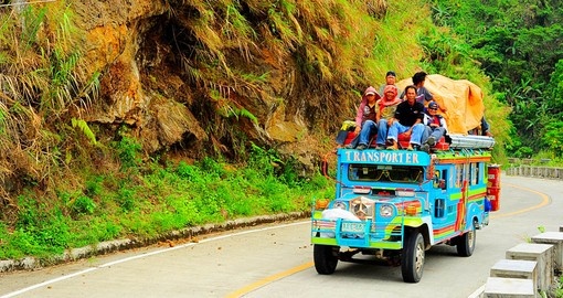 Passengers sit atop a very full jeepney