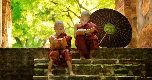 Young buddhist monks reading outdoors sitting outside monastery