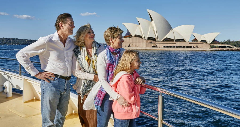 Grandparents, daughter, and granddaughter on a cruise passing Sydney Opera House.